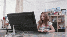 a young girl is typing on a keyboard in front of a computer screen