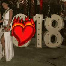 a woman in a white dress is standing in front of a large number 18