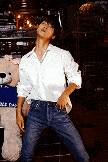 a man in a white shirt and blue jeans is dancing in front of a stuffed animal that says nice day