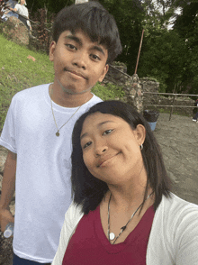 a boy and a girl are posing for a picture and the girl is wearing a red shirt