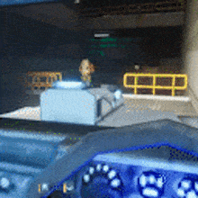a steering wheel is shown in a video game with a yellow railing in the background