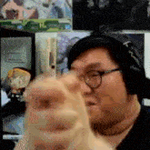 a man wearing headphones and glasses is pointing at something .