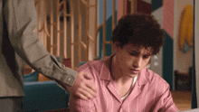 a man is putting his hand on a man 's shoulder while sitting at a table .