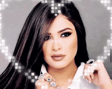 a woman with long dark hair is wearing a white shirt and rings on her fingers