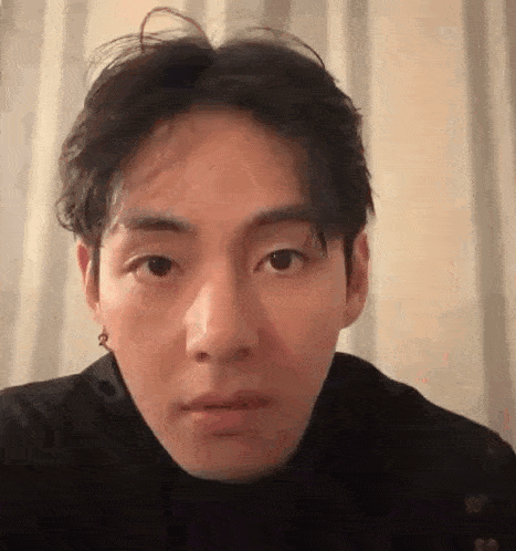 a close up of a person 's face with a turtleneck and earrings on .
