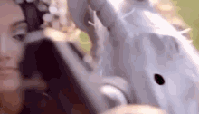 a woman with a flower crown on her head is standing next to a statue of a bird .