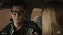 a man wearing glasses is sitting in a car with a woman .