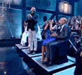 a group of people are sitting on a stage in front of a crowd .