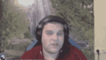 a man wearing headphones is sitting in a chair in front of a waterfall .