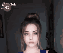 a young woman is making a funny face with her finger on her lips while wearing a blue shirt .
