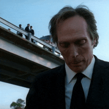 a man in a suit and tie is looking down at something
