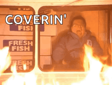 a man is driving a truck with flames coming out of the window and the words coverin ' on the bottom .