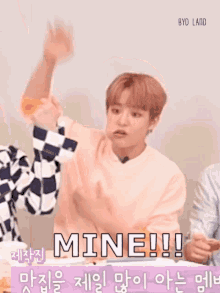a young man in a pink sweater is saying mine in a foreign language .