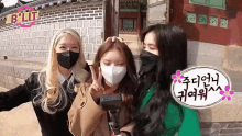 three girls wearing masks are standing in front of a building .
