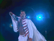a man without a shirt is standing in front of a blue light and holding a microphone