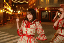 a woman in a red and white floral dress stands in front of a grand magasin