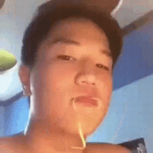 a close up of a young man 's face with a toothpick in his mouth .