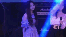 a woman in a purple dress is standing on a stage with a microphone in her hand .