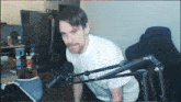 a man is sitting in front of a microphone with a bottle of pringles chips in the background
