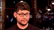 a man wearing glasses and a black shirt is looking at the camera