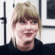 a close up of taylor swift 's face with a ponytail and bangs .