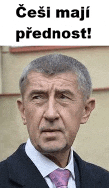 a man in a suit and tie is looking at the camera with a sign behind him .