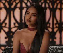 a woman is sitting on a couch wearing a red dress and a choker .