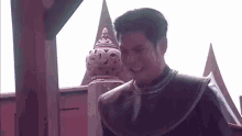 a man in a traditional costume is smiling in front of a building .