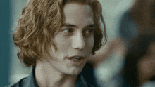 a close up of a young man 's face with long red hair