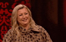 a woman in a plaid shirt is smiling in front of a black background