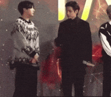 a man in a black suit is standing next to a woman in a sweater that says ' i love you ' on it