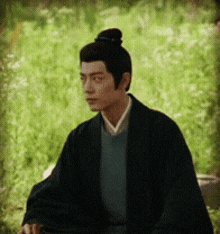 a man with a bun on his head is wearing a black jacket
