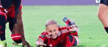 a soccer player is smiling while laying on the grass during a game .