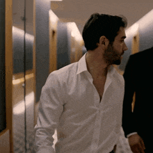 a man in a white shirt is standing in a hallway