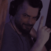 a man with a beard wearing headphones is giving a thumbs up sign .