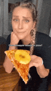 a woman is holding a slice of pizza with pineapple on it .