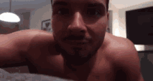 a shirtless man with a beard is laying on a bed .