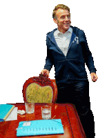 a man wearing a blue sweatshirt with the letter t on it stands at a table