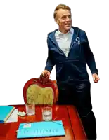 a man wearing a blue sweatshirt with the letter t on it stands at a table