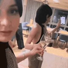 a woman in a black top is holding a glass of champagne