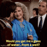 a woman is holding a glass of water while talking to a man