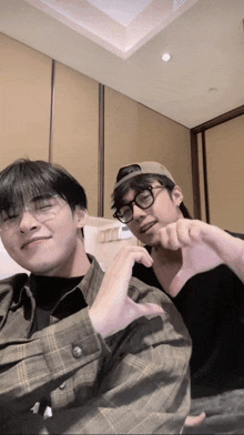 a man wearing glasses and a hat is sitting next to another man wearing glasses