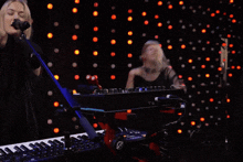 a woman is singing into a microphone while another woman plays a keyboard