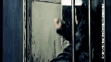 a man in a gas mask is behind bars with chinese writing on the bottom of the screen .