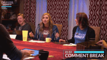 a group of people are sitting around a table wearing dragons things t-shirts