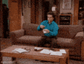 a man is sitting on a couch drinking coffee