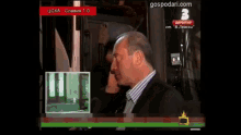 a man in a suit stands in front of a tv screen that says gospodari.com