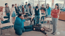 a group of people are standing around a man laying on the floor in a classroom ..