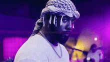 a close up of a man wearing a head scarf and a chain .