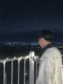 a person standing on a balcony looking at a cell phone